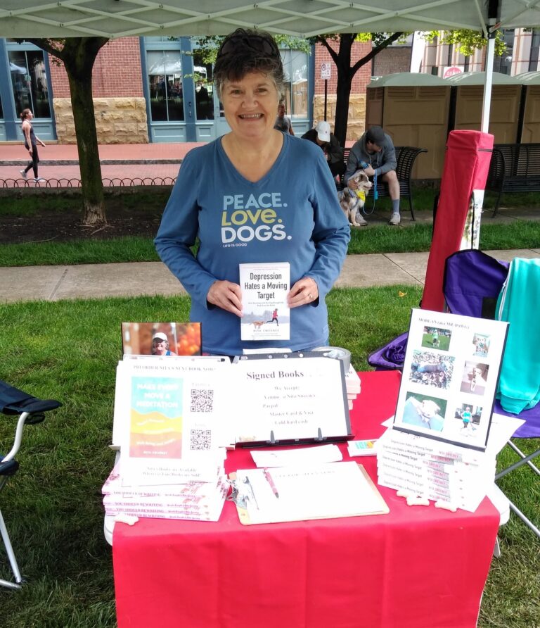 Pet Promise Rescue Run - woman holding book at outdoor vendor event