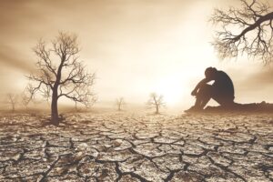 body discomfort - man sitting on cracked earth