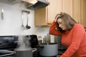 5 conditions - Woman with hand on head leaning over a hot stove